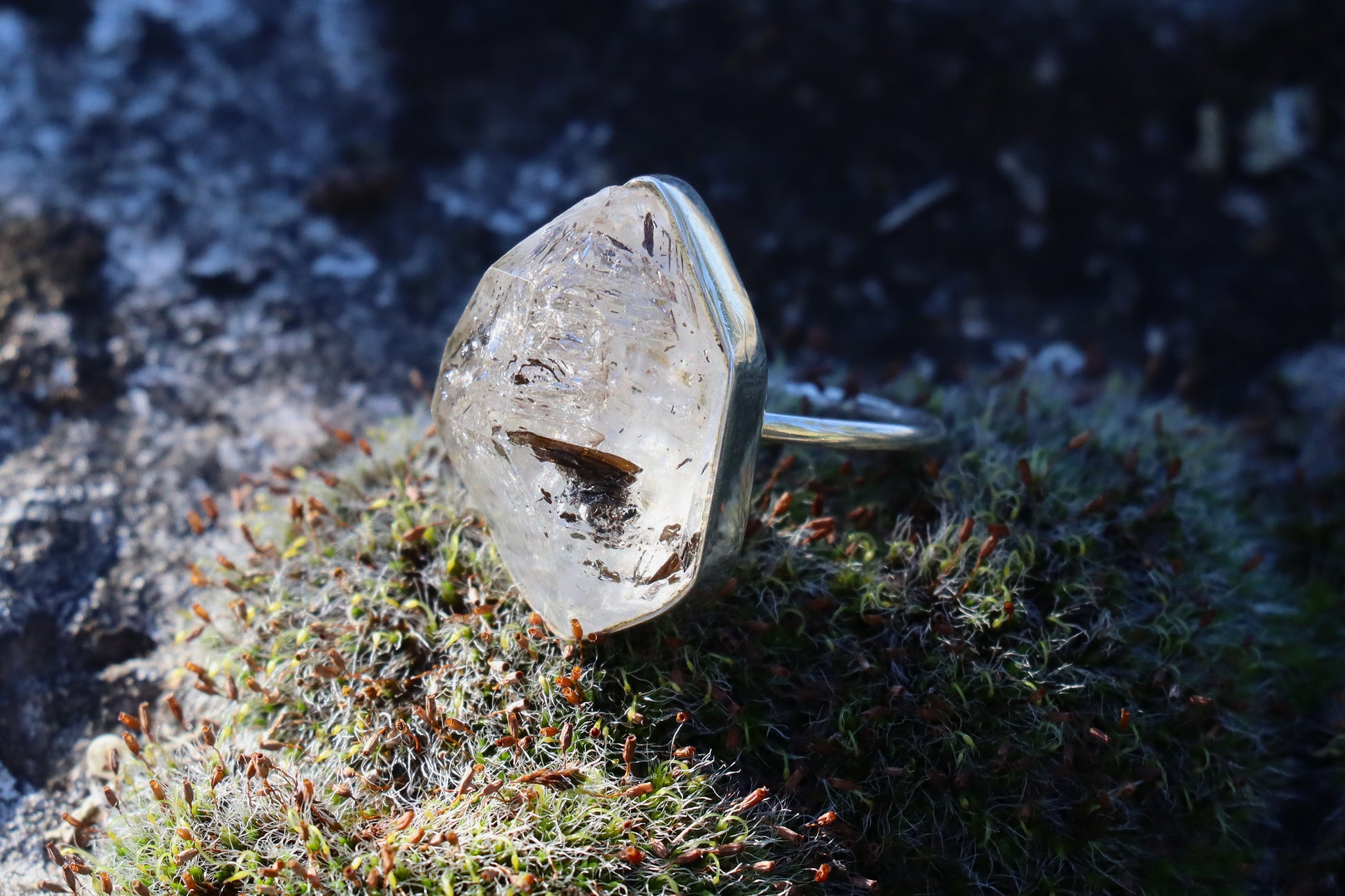 Black rutilated quartz ring in sterling silver displayed on natural moss