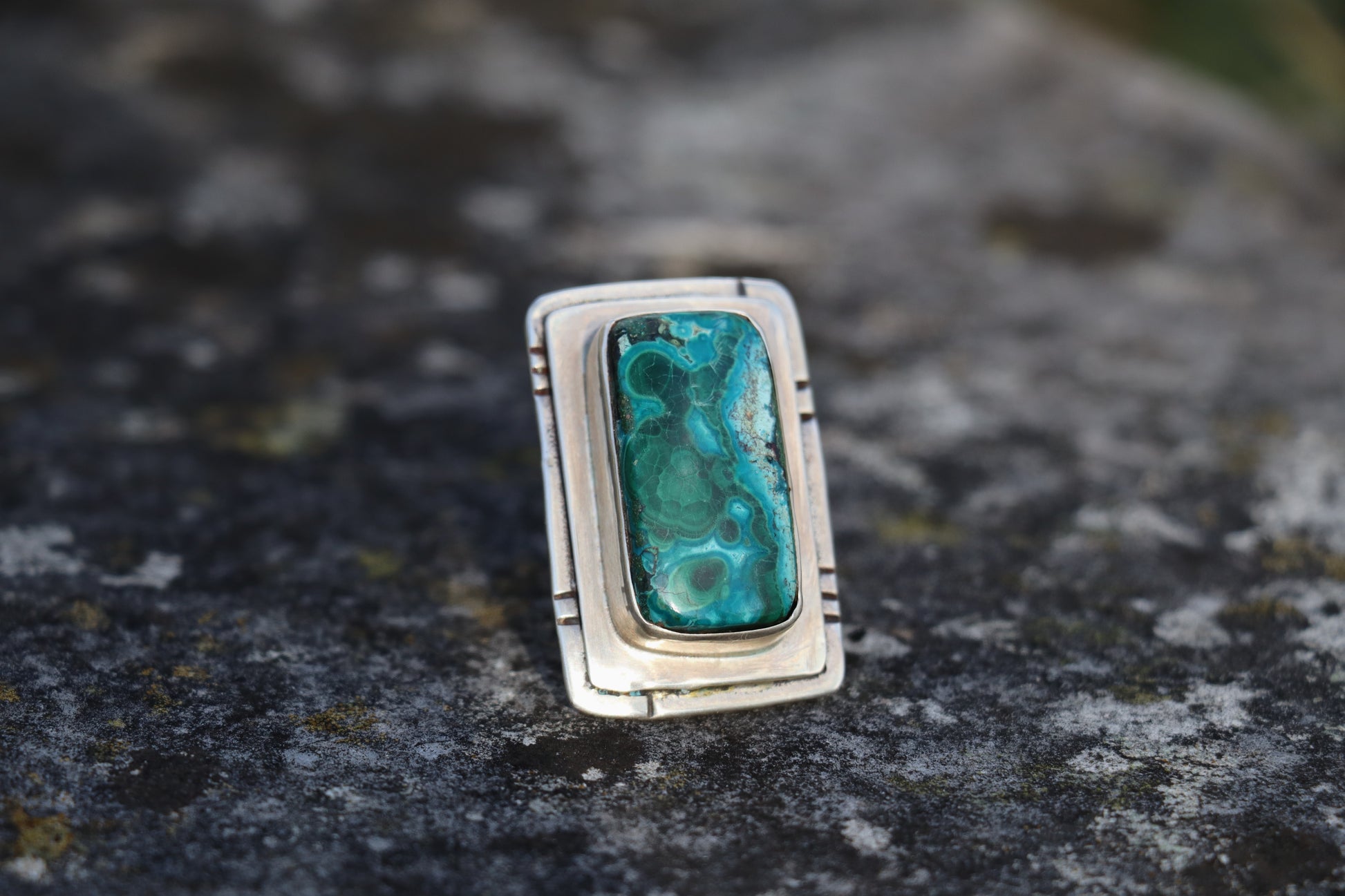 Front view of a large Chrysocolla Malachite ring set in sterling silver, highlighting the rectangular natural stone with deep teal and green swirls. Bold statement crystal ring for emotional healing.
