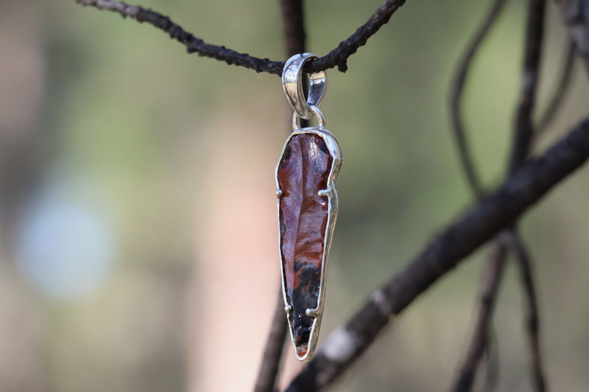 Sterling Silver pendant featuring a raw Mahogany Obsidian gemstone. Close-up highlighting the stone's deep brown and black volcanic streaks.
