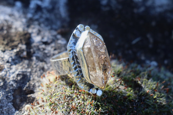 Smoky Quartz Crystal Ring on natural rock, emphasizing its earth connection and properties for clearing stagnant energy.