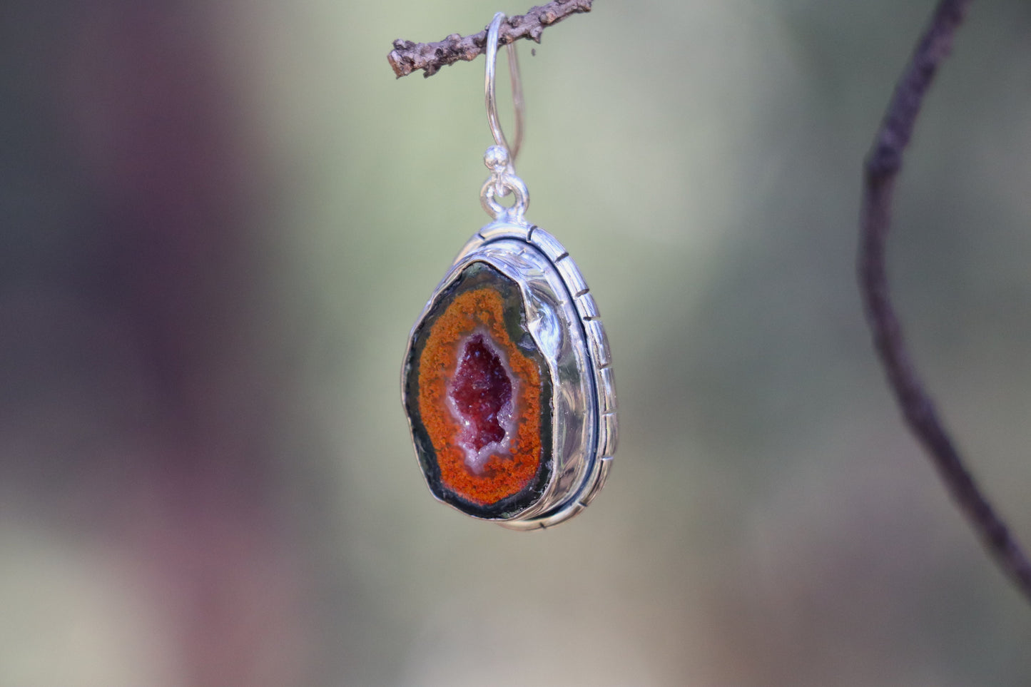 side view of a Tabasco Geode earring showcasing the handcrafted 925 sterling silver bezel and natural geode texture. The stone’s orange rim and inner crystal glimmer reflect its grounding, transformative Saturn–Pluto energy.
