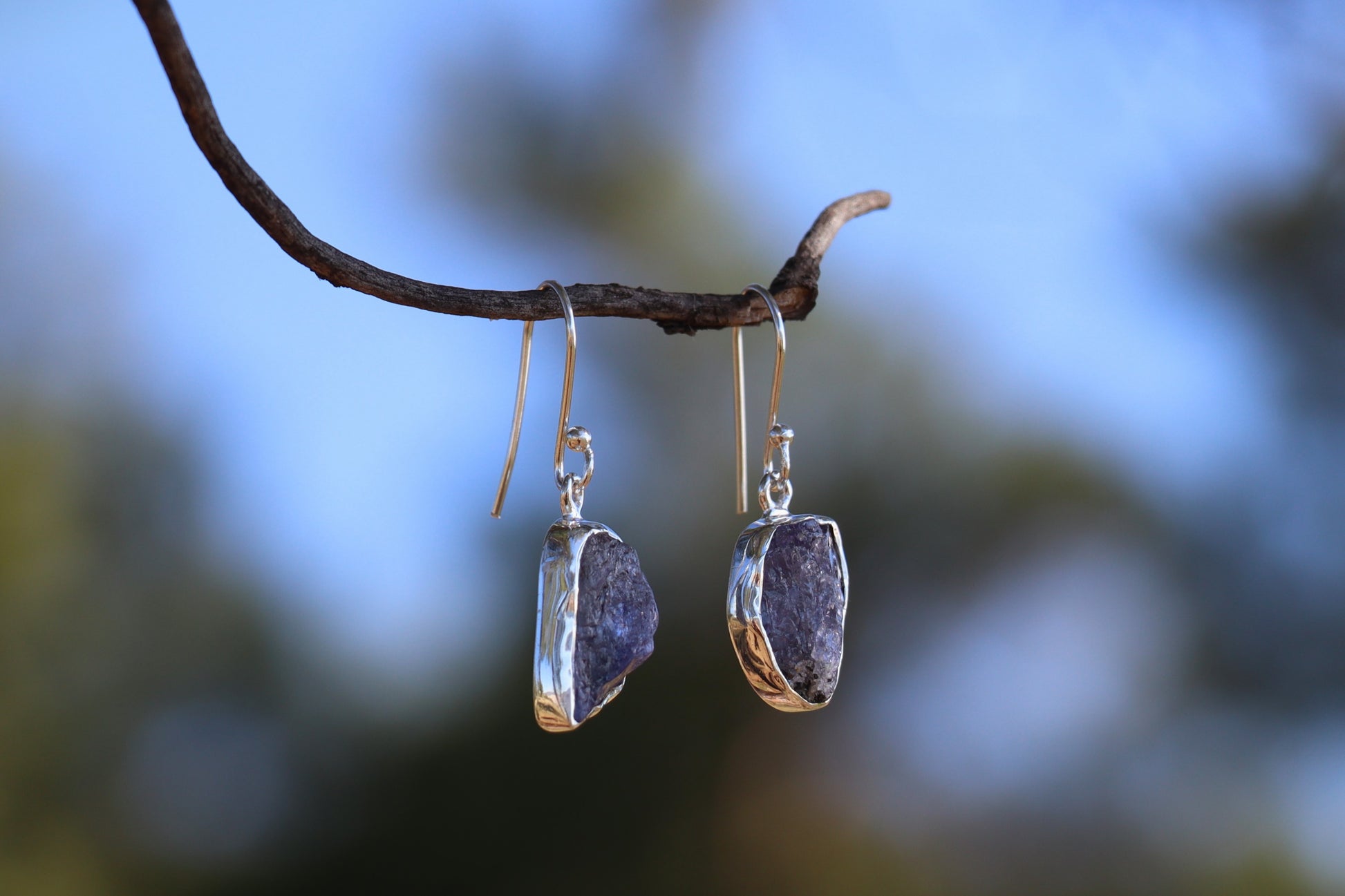 Raw amethyst crystal earrings wrapped in 925 sterling silver, close-up of natural purple gemstone dangles