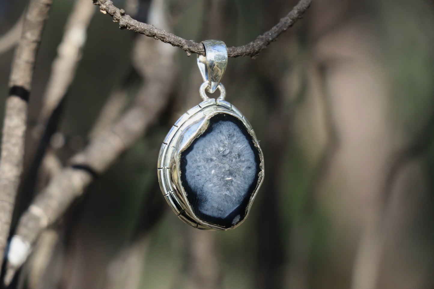 Close-up of coconut geode druzy quartz pendant in silver frame, highlighting the sparkling crystal core