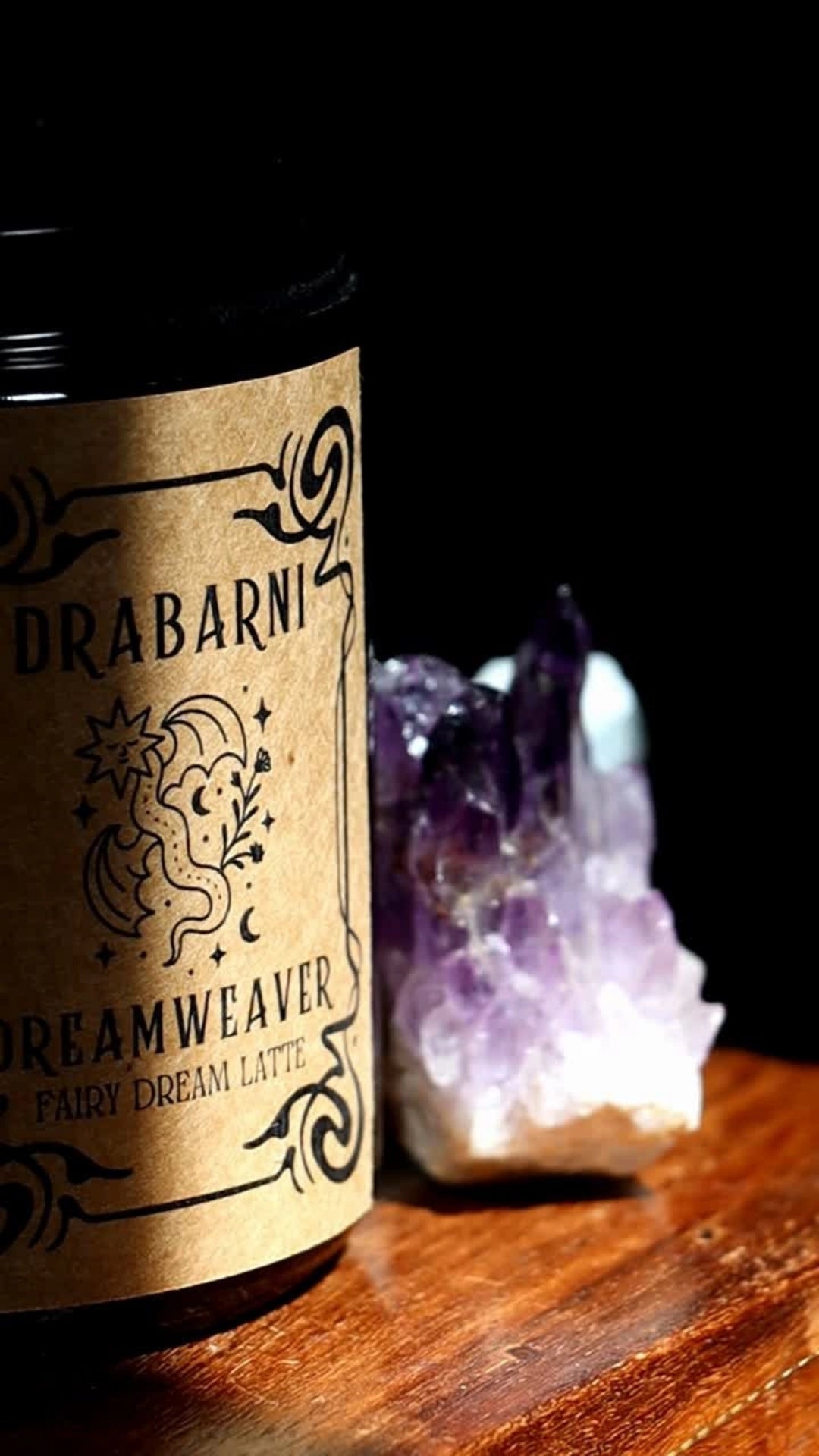 Dreamweaver Fairy Dream Latte by Drabarni Medicine. A caffeine-free botanical blend for lucid dreaming and emotional healing with Butterfly Pea, Rose, and Cardamom. Pictured next to a purple amethyst crystal for ritual dream work and sleep support.