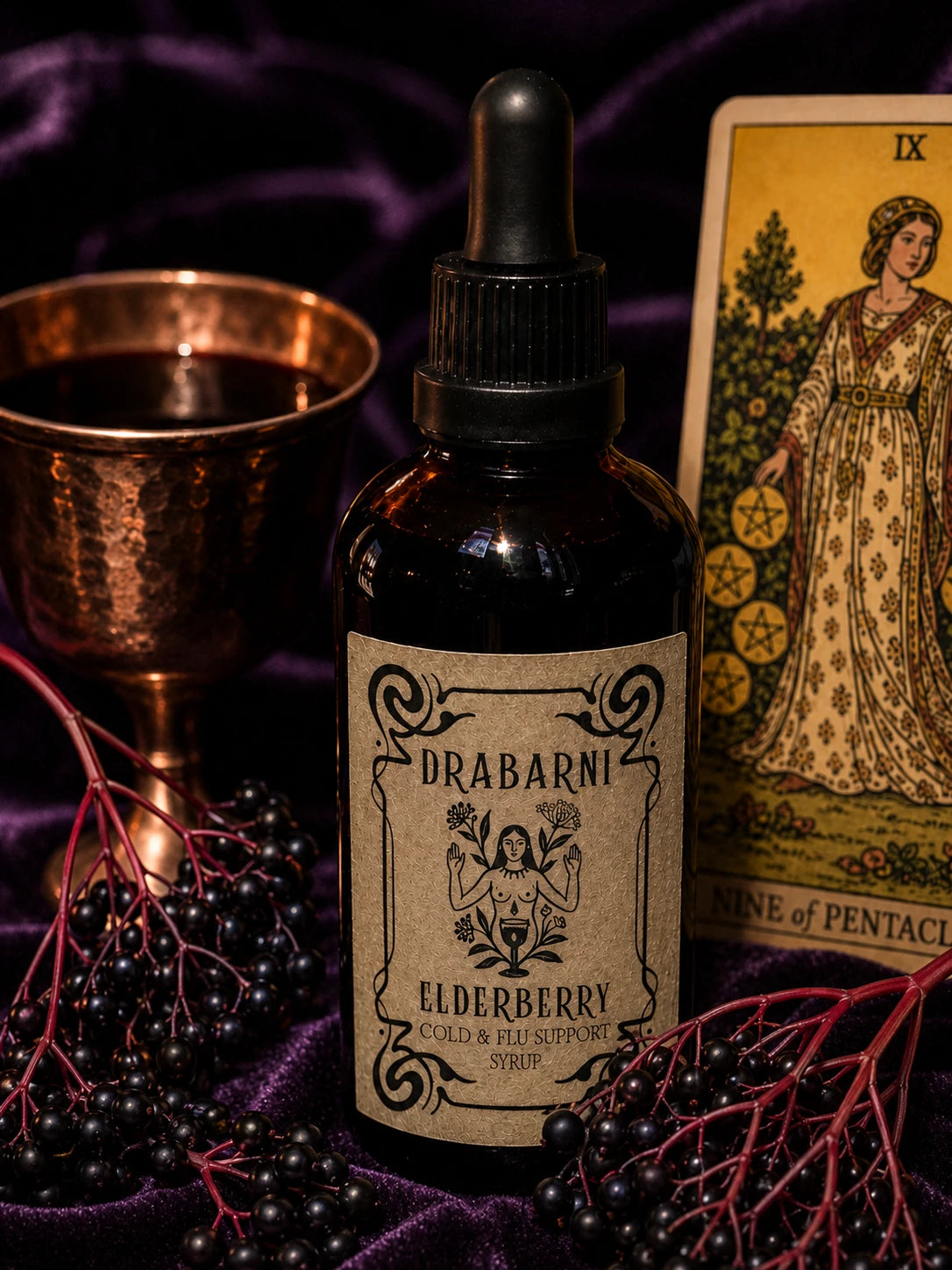 Drabarni organic Elderberry syrup for kids and adults immune support against cold and flu. A potent antiviral elderberry liquid medicine blended with turkey tail mushroom, echinacea, and turmeric. Handcrafted by a green witch apothecary for seasonal wellness on a purple velvet altar.